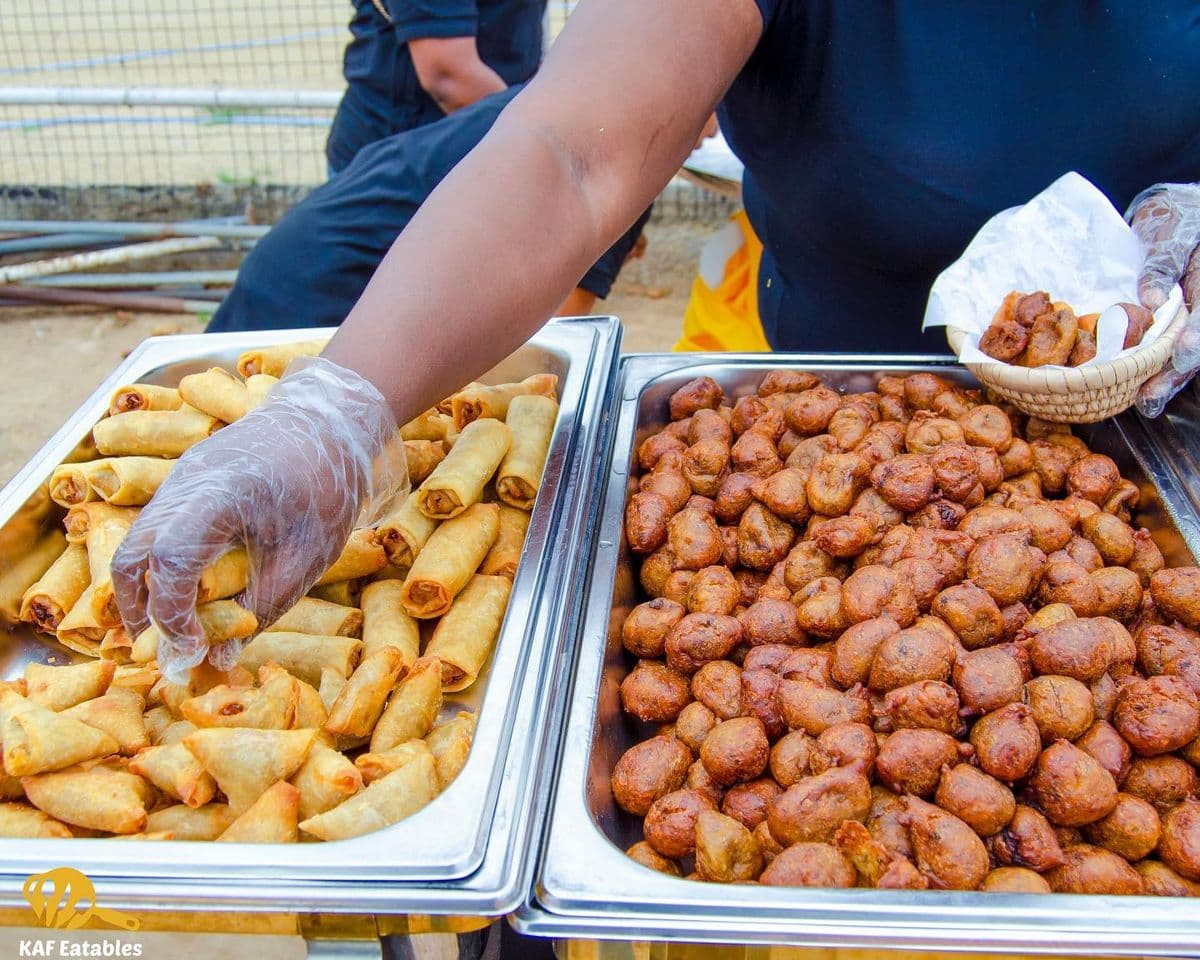 KAF Eatables staff serving trays of spring rolls and puff puff at an event
