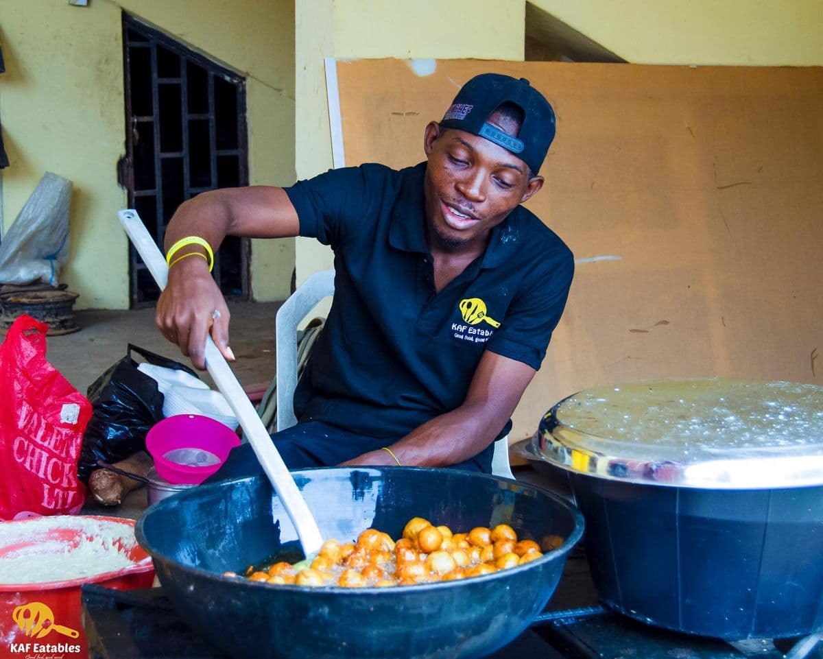 KAF Eatables cook frying a fresh batch of puff puff in a large pan